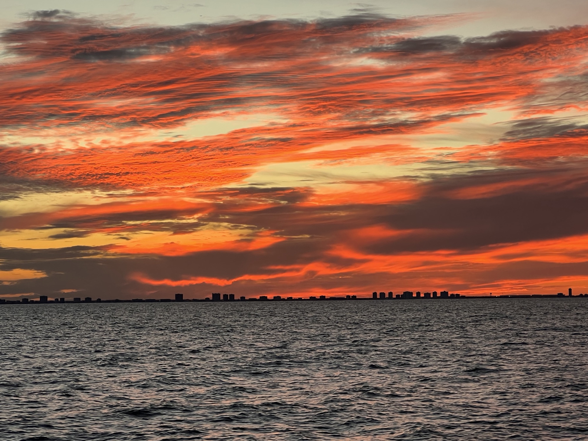 Fiery red-orange sunset sky over dark water